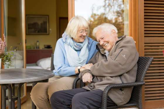 Ein älteres Paar sitzt draußen lachend, Spendenmöglichkeit, jede Spende zählt, Diakonie Hospiz Volksdorf