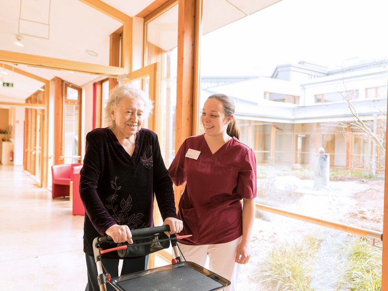 Seniorin geht mit Pflegerin im Hospiz spazieren