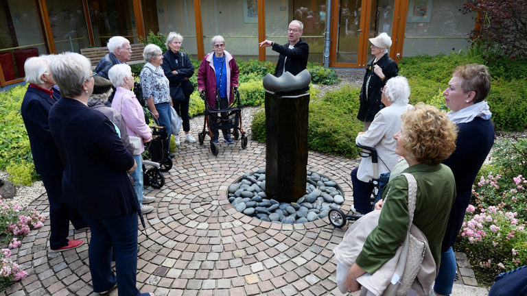 Gruppe steht um eine Skulptur im Hospizgarten im Diakonie Hospiz Volksdorf