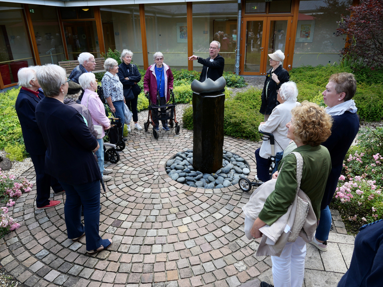 Gruppe steht um eine Skulptur im Hospizgarten im Diakonie Hospiz Volksdorf