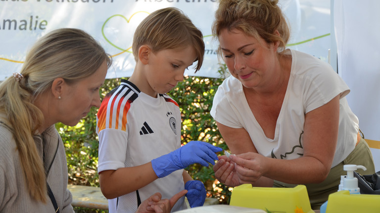 Ein Kind mit blauen Einmalhandschuhen bei einer Simulationsübung mit Mitarbeiterinnen an den Ständen des Gesundheitscampus Volksdorf der Immanuel Albertinen Diakonie beim Stadtteilfest Volksdorf in Hamburg Ein Kind mit blauen Einmalhandschuhen bei einer Simulationsübung mit Mitarbeiterinnen an den Ständen des Gesundheitscampus Volksdorf der Immanuel Albertinen Diakonie beim Stadtteilfest Volksdorf in Hamburg
