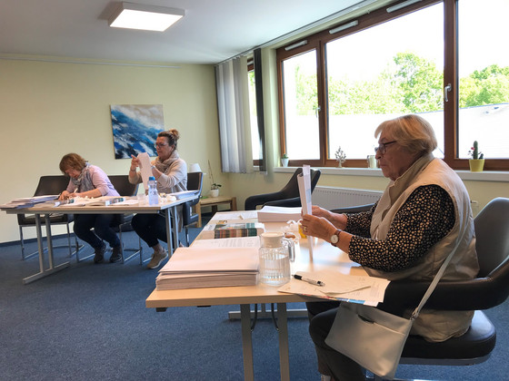Ehrenamtliche sitzen am Tisch und bereiten das Magazin für den Versand vor, neue Ausgabe der Zeitschrift Lebenswert, Albertinen Hospiz Norderstedt, Diakonie Hospiz Volksdorf